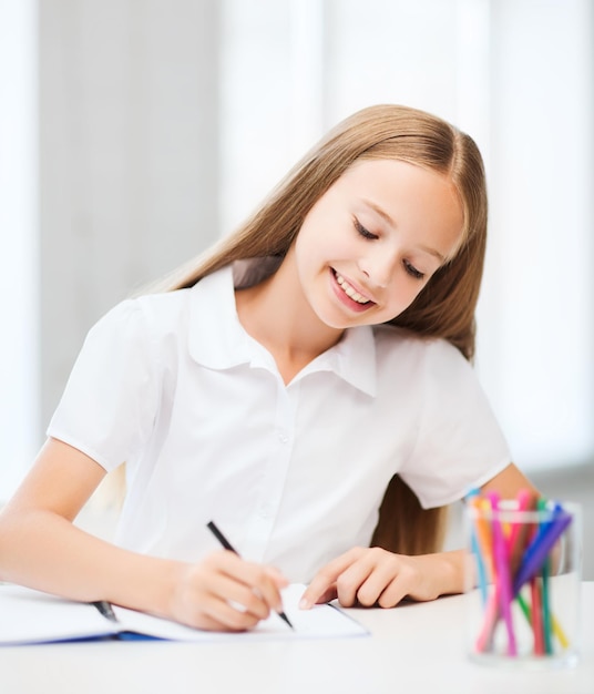 education and school concept - little student girl drawing at school