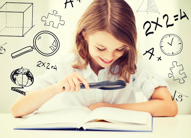 education and school concept - little student girl reading book with magnifier at school