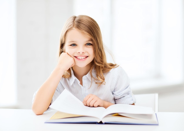 education and school concept - little student girl studying at school