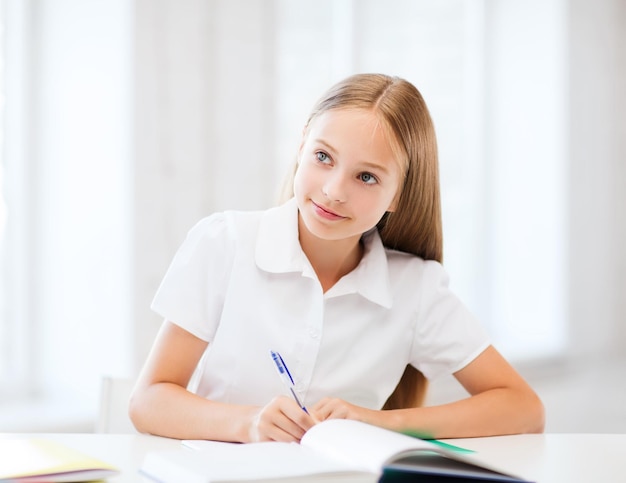 education and school concept - little student girl studying at school