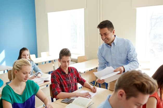 education, school, learning and people concept - group of students and teacher with test results in classroom