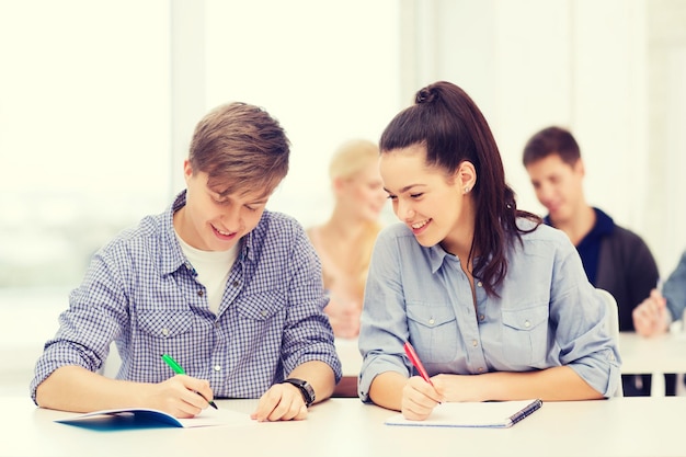 education, school and people concept - two teenagers with notebooks at school