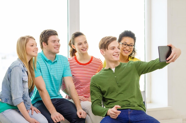 education and technology concept - smiling students making picture with tablet pc computer at school