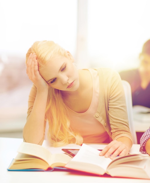 education, technology and internet concept - tired teenage girl student with tablet pc and books preparing for exam