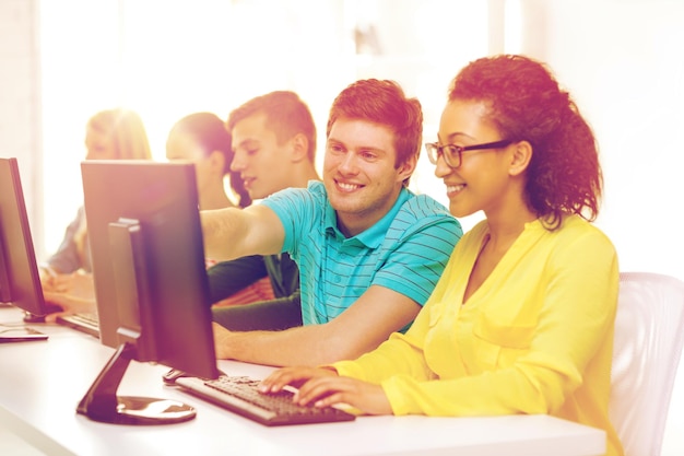 education, technology and school concept - smiling students in computer class at school