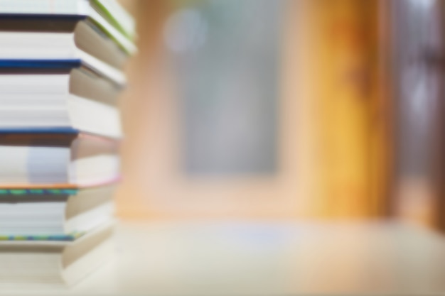 Photo education and training background. pile of books on the desk, window and bookcase defocused.