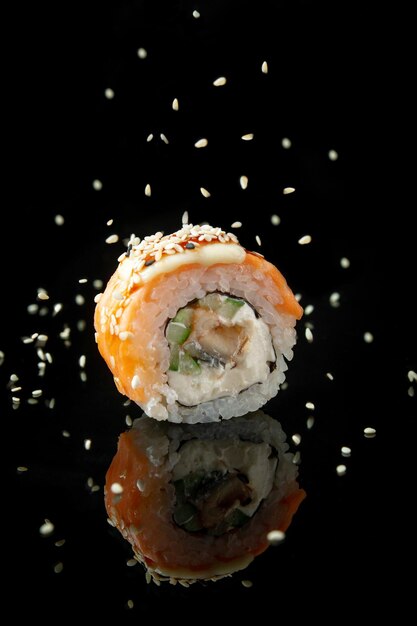 eel sushi on black background with reflection sprinkled with sesame seeds