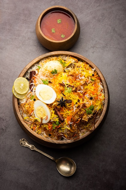 Egg Biryani - Basmati rice cooked with masala roasted eggs and spices and served with yogurt, selective focus