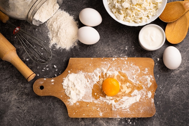 Egg in flour on a wooden board. Cooking homemade dessert. Healthy diet. Top view.