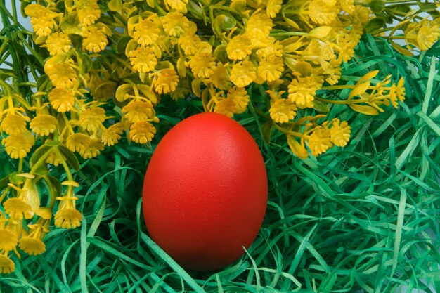 Egg painted red on yellow straw, symbolizing Easter.