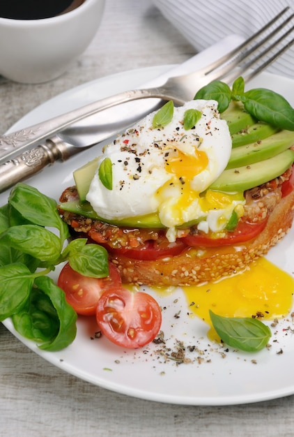 Egg poached on a toasted slice of baguette with tomato spicy ham and avocado