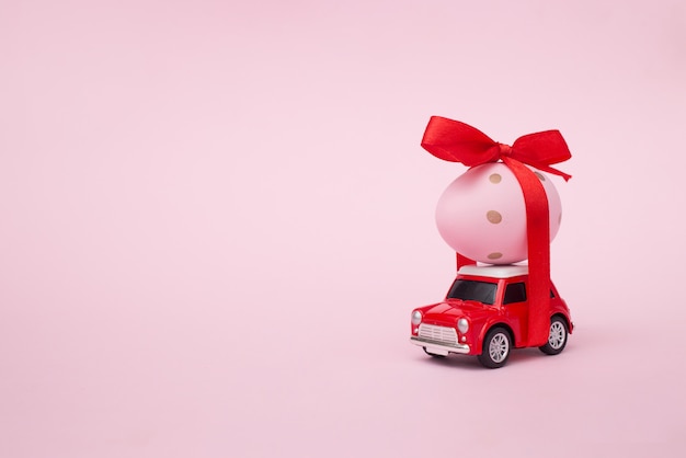 egg on red toy car on pink pastel wall