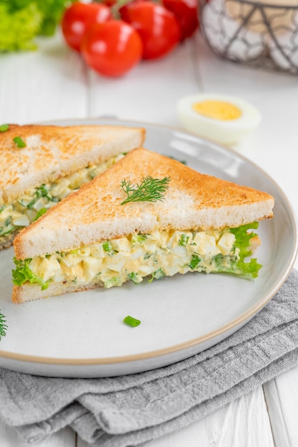 Egg salad sandwich with toasted bread and lettuce on a white wooden background Selective focus