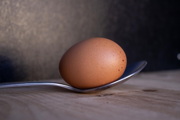 Egg in spoon on top of wooden board with black background