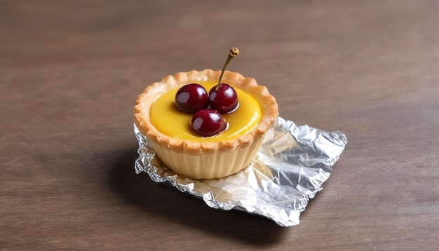 egg tart in aluminum foil cup with red cherry on wood table