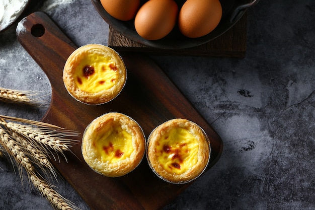 Egg tarts on wooden board on dark background