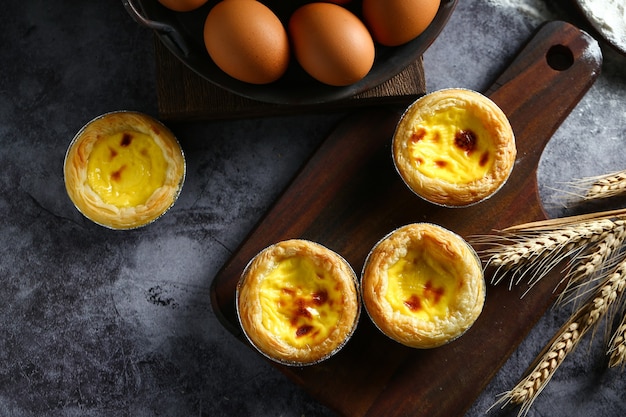 Egg tarts on wooden board on dark background