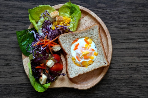 Egg toast with mixed salad for breakfast time on a wooden plate