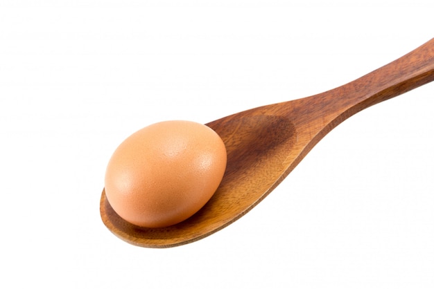 Egg in wooden spoon on white