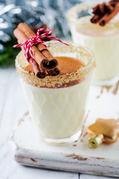 Eggnog Traditional Christmas drink milkshake with cinnamon on light old table.