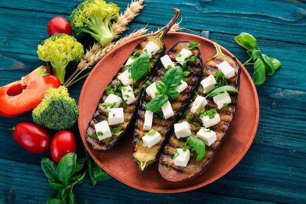 Eggplant grilled with feta cheese and basil Healthy food On a blue wooden table Top view Free space for text