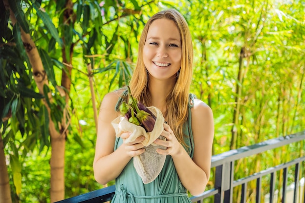 Eggplant in a reusable bag in the hands of a young woman zero waste concept