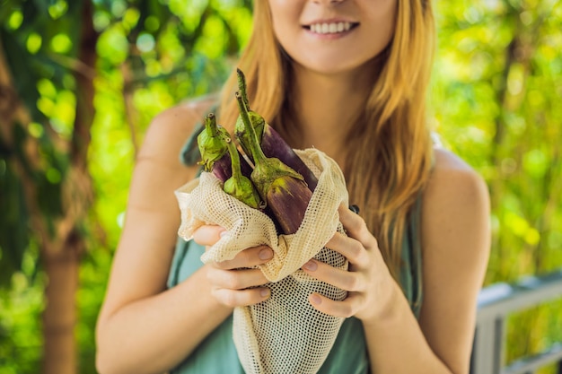 Eggplant in a reusable bag in the hands of a young woman Zero waste concept