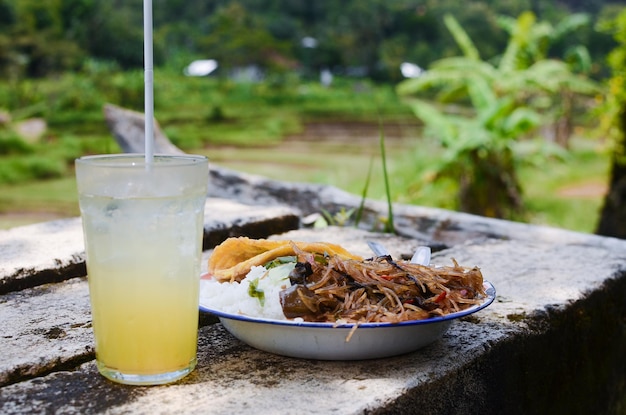 Eggplant rice noodles and omelet served with fresh orange juice