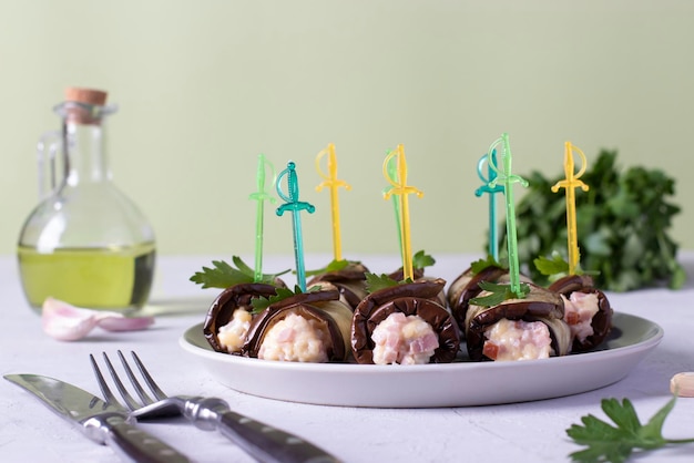 Eggplant rolls with ham and cheese on a plate on light gray background Horizontal format