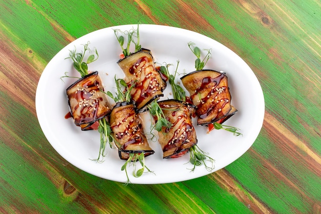 Eggplant vegetable rolls with unagi sauce On a colored wooden background Vegetarian dish