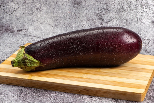 Eggplant under wooden board being sprinkled with water to be prepared for salad