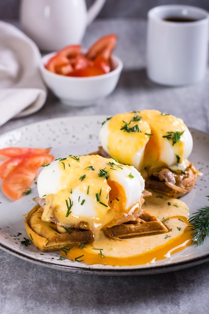 Eggs benedict and bacon on a crispy waffle on a plate for homemade breakfast Vertical view