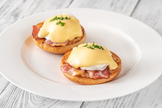 Eggs Benedict with bacon on white plate