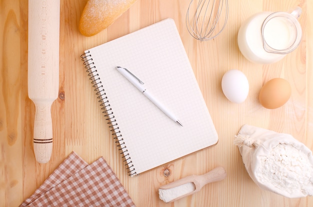 Eggs flour milk and whisk on a wood background