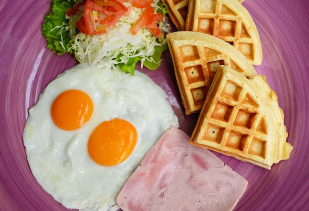 Eggs with ham and salad and belgian waffles close up