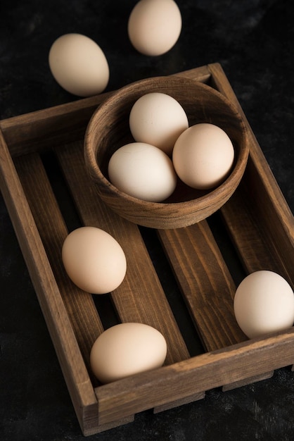 Eggs on wood board in wooden bowl dark background