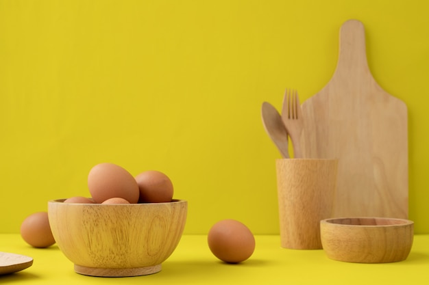 eggs and wooden kitchenware on yellow background