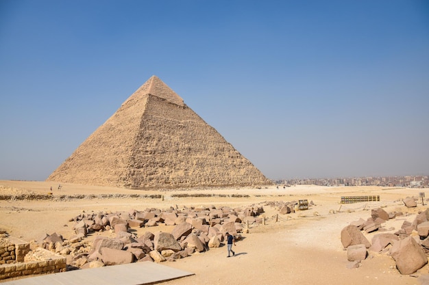 Egypt The Pyramid of Cheops Khafre Mikerin A man walks past a pyramid with a sky background