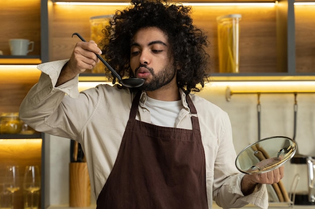 Egyptian man chef tastes cooked soup from ladle in kitchen