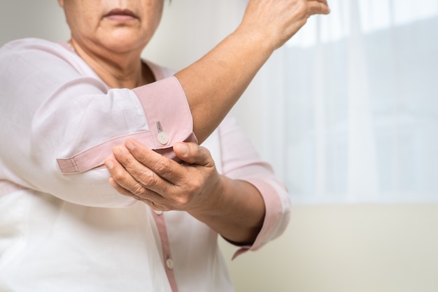 Elbow pain old woman suffering from elbow pain at home, healthcare problem of senior concept