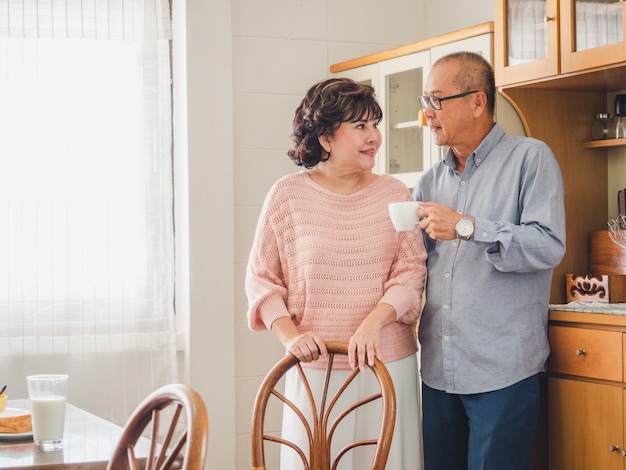 Elder couples stand to drink coffee in the kitchen in the morning