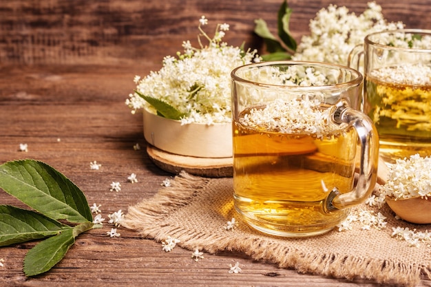 Elderberry flower tea. Refreshing summer drink, healthy lifestyle concept. Sackcloth napkin, vintage wooden table, close up