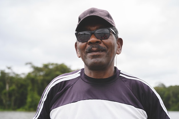 Elderly African-American male with sunglasses and cap rowing a boat on a river in Costa Rica