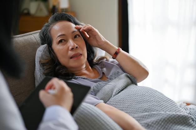 An elderly Asian female patient talking with her doctor in the recovery room