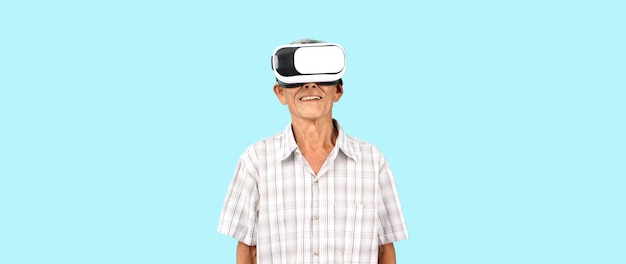 Elderly Asian man playing VR video game with virtual reality goggles blue background in studio