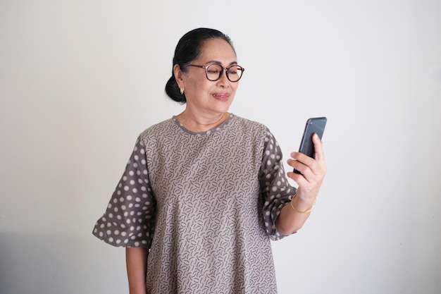 Elderly Asian woman smiling while looking to her mobile phone