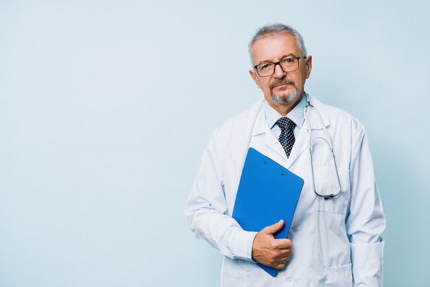 Elderly bearded male doctor in white uniform with a stethoscope with a blue folder.