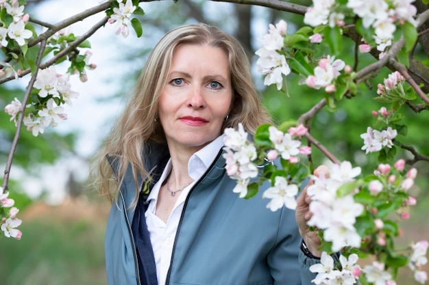 An elderly beautiful woman posing in a spring blooming garden