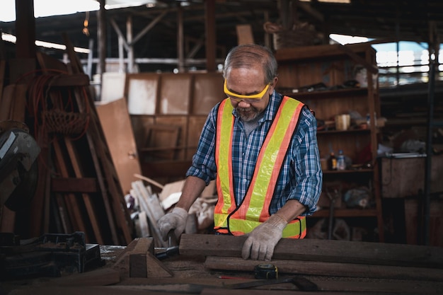 An elderly carpenter works the wood with meticulous care