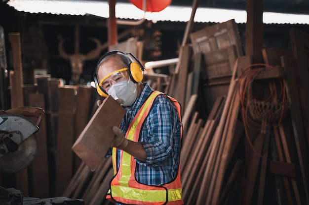 An elderly carpenter works the wood with meticulous care